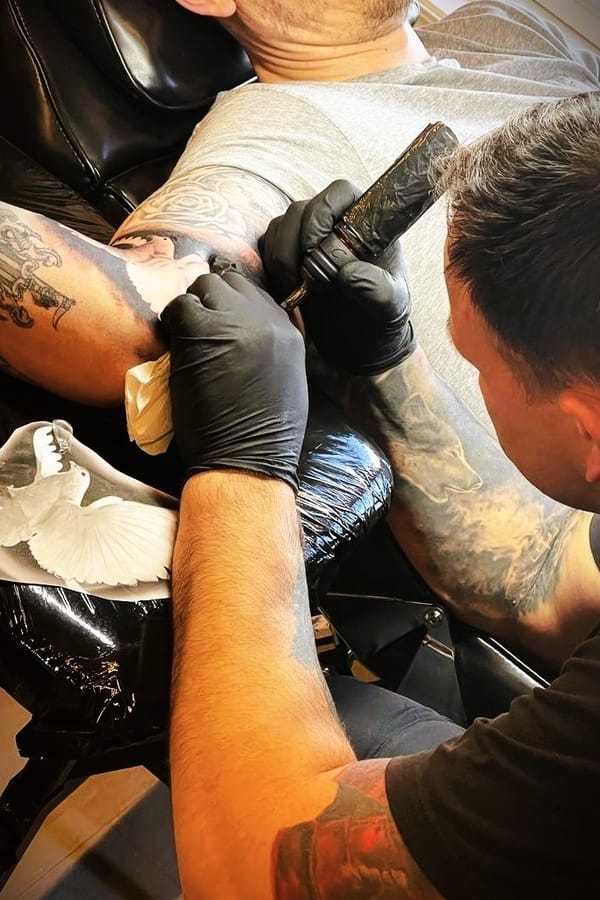 An Image of Ed tattooing bird on client arm